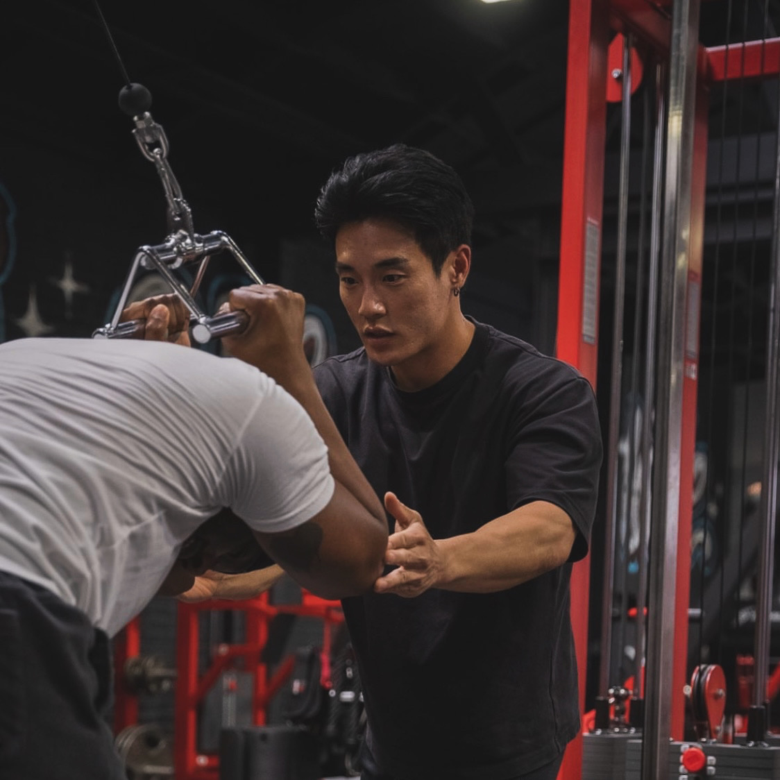 Kevin Bae coaching a client through a cable exercise.