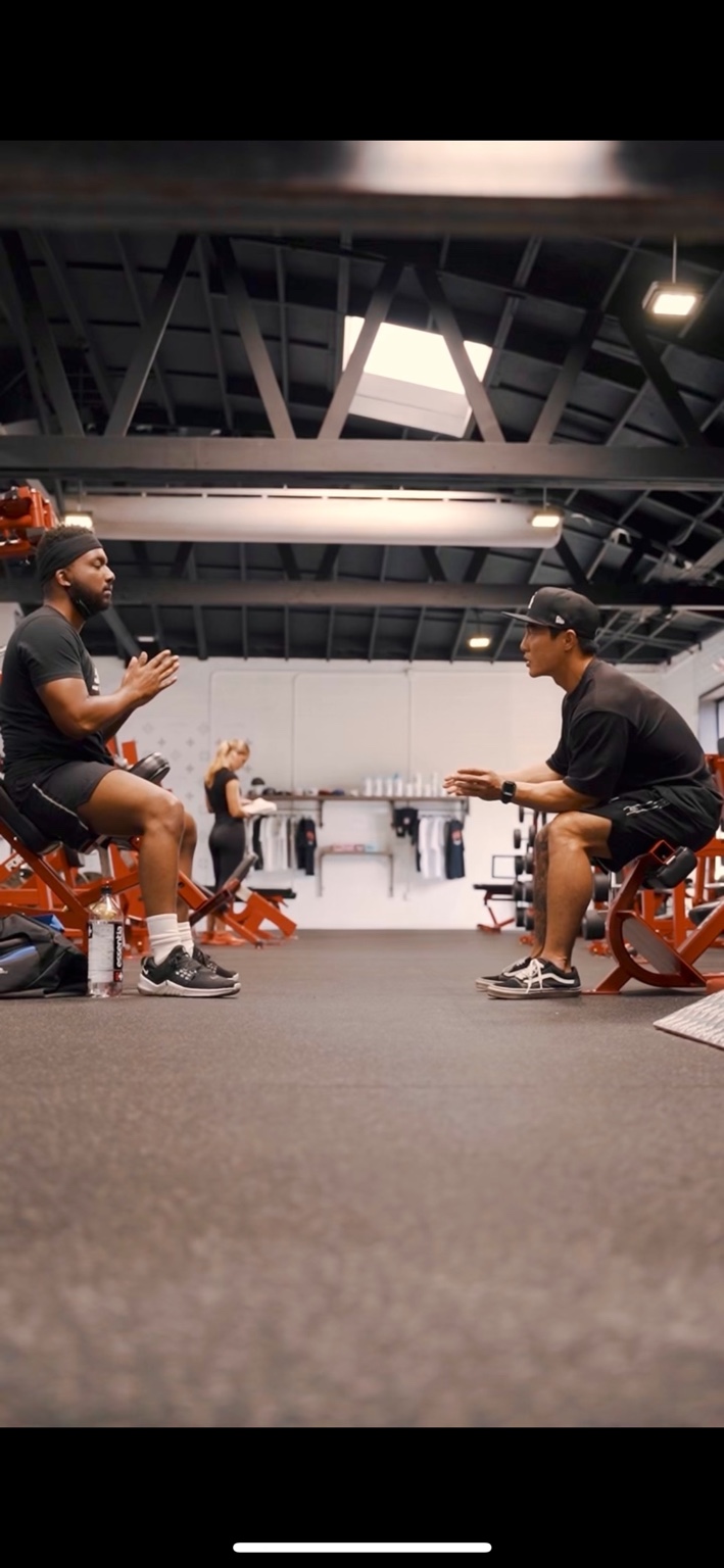 Kevin Bae seated opposite a client during a conversation in the gym.